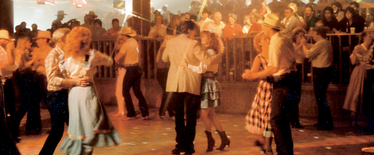 People square dancing on lively dance floor in front of onlookers.